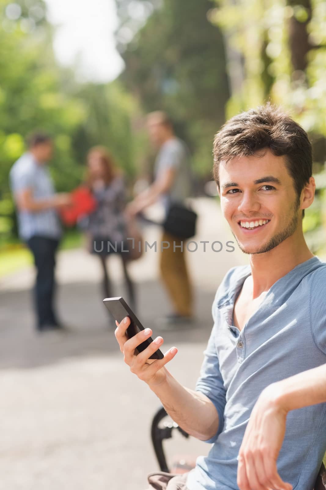 Handsome student sending a text outside at the university