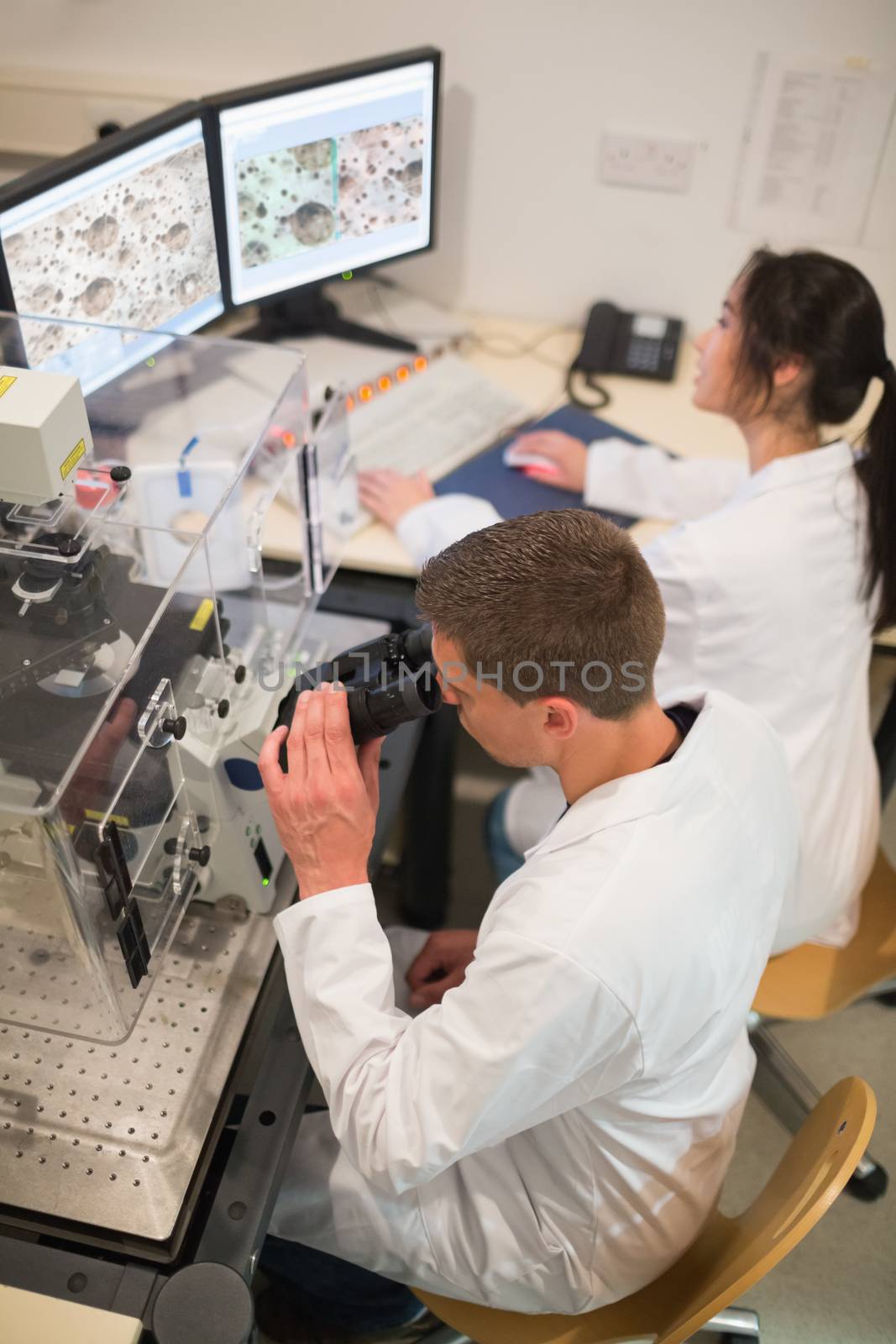Biochemistry students using large microscope and computer at the university