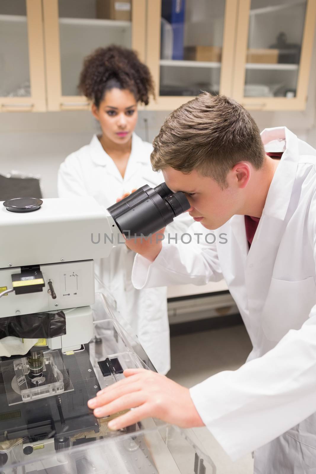 Young scientist working with microscope at the university