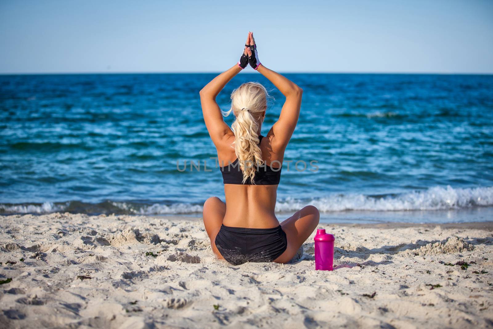 beautiful young woman sitting in yoga pose at the beach  by Anpet2000