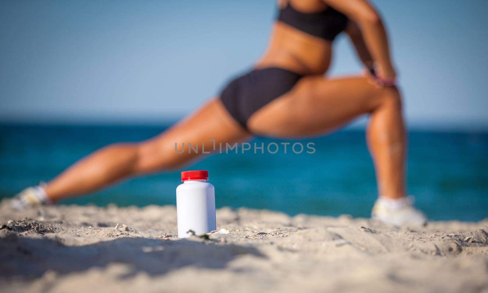 bottle of sports food on sand against the training girl