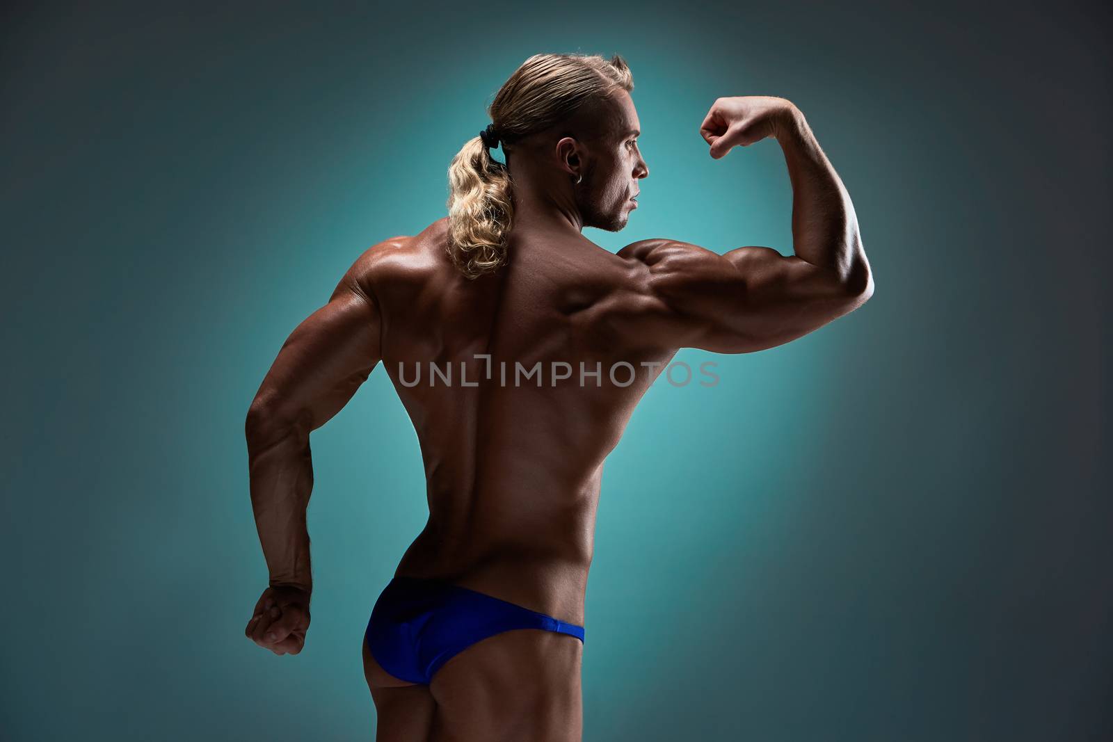 torso of attractive male body builder on blue background.