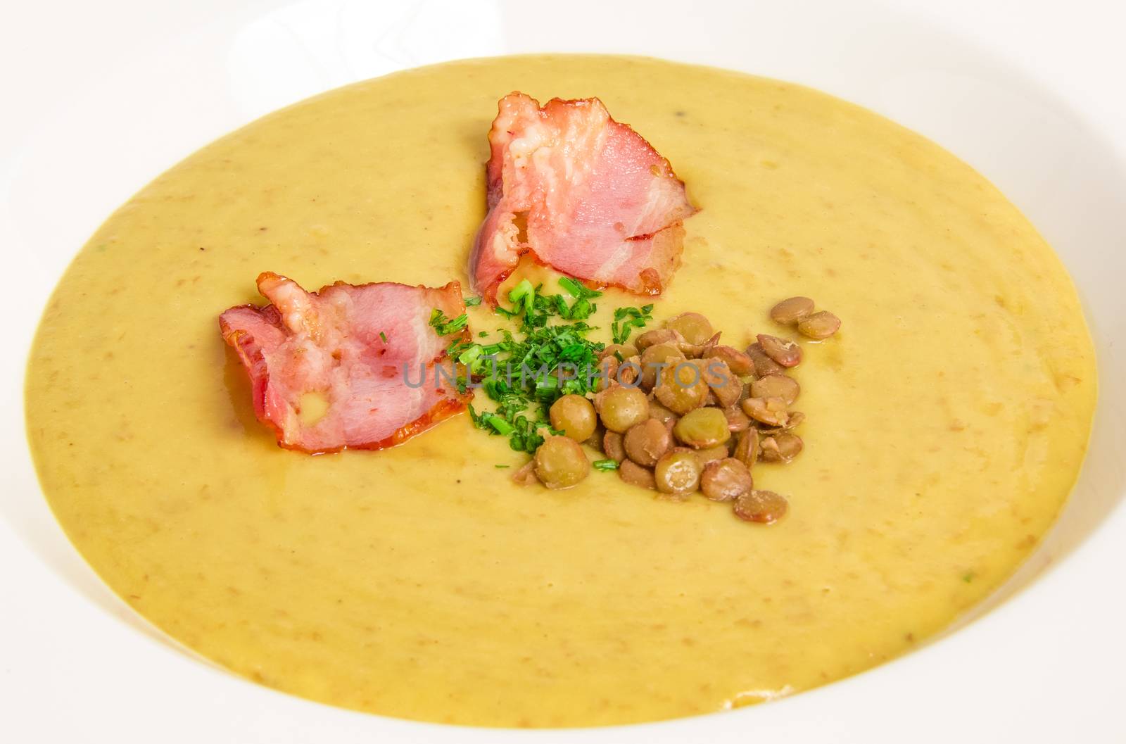 Pea soup with bacon on white background