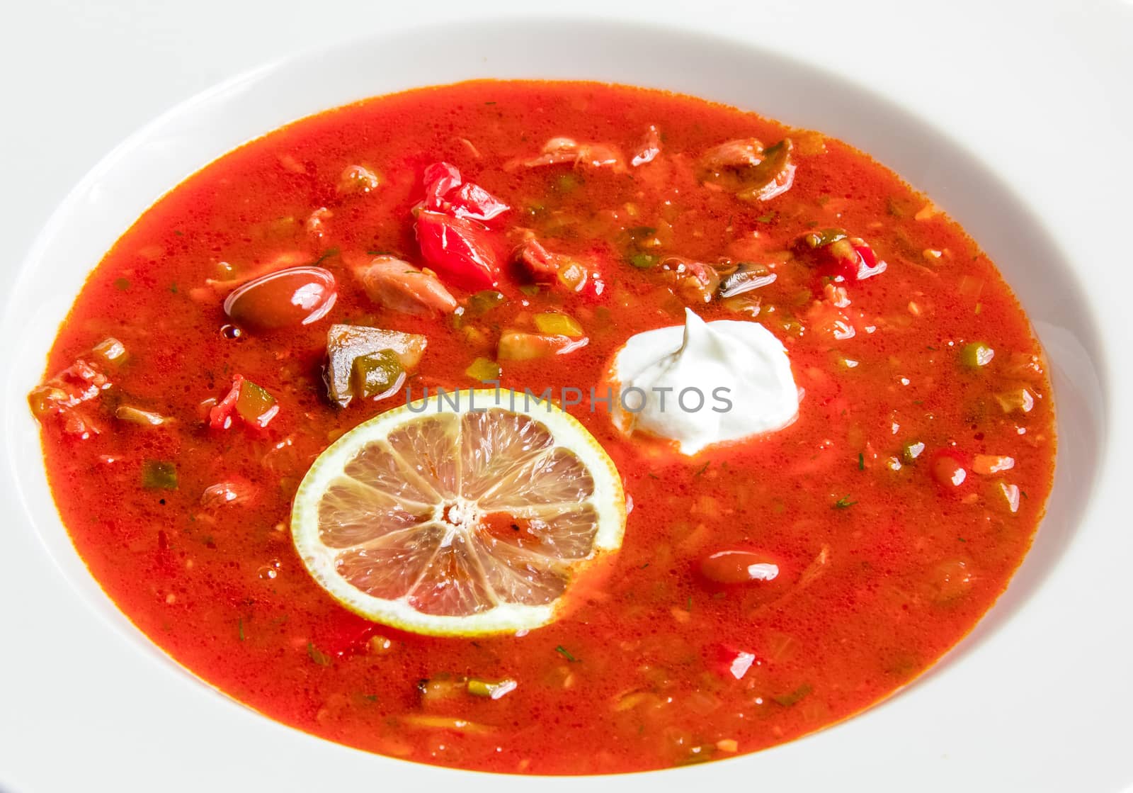 Red vegetable soup with beans and lemon. On white background
