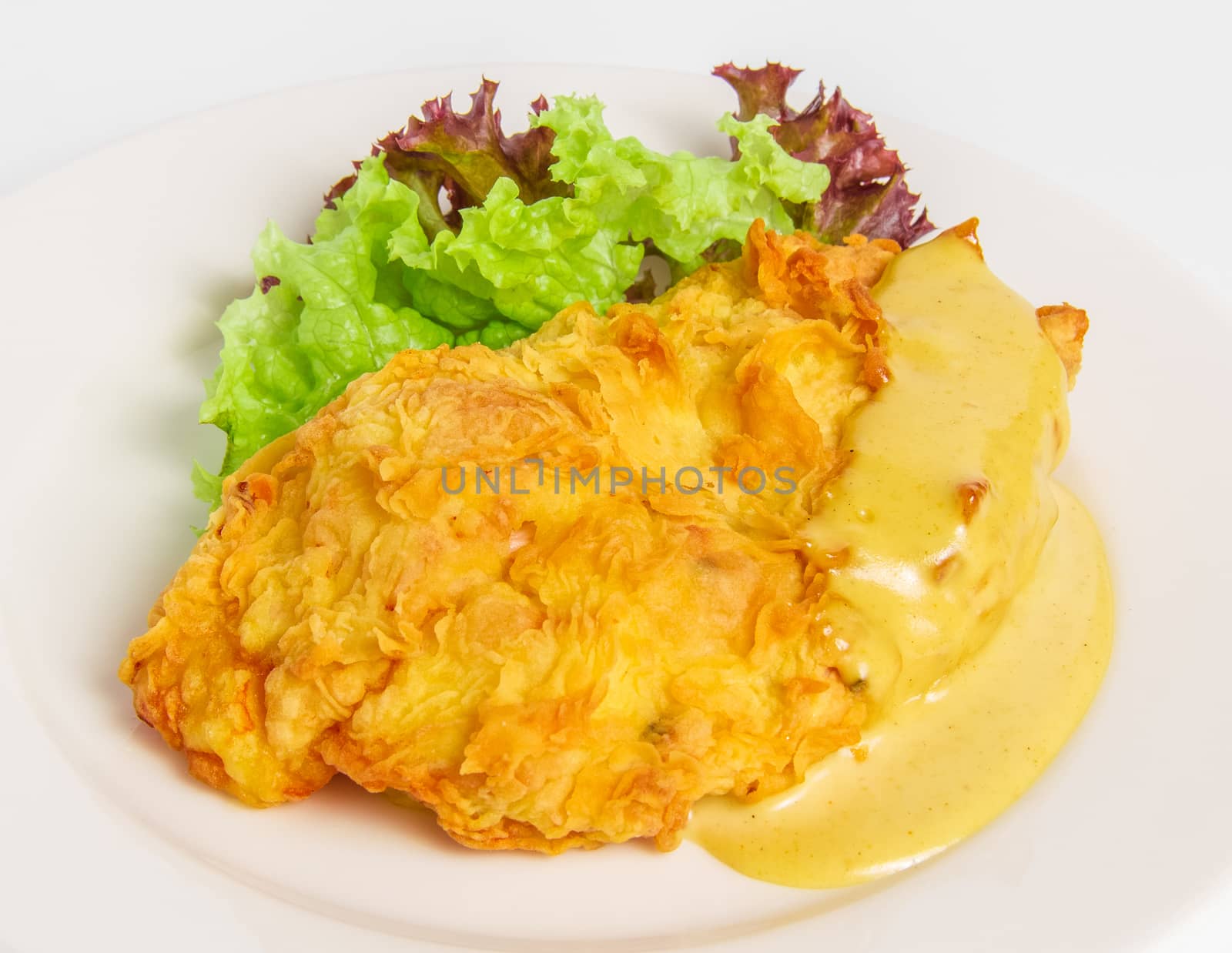 chicken fillet with cheese in batter with honey-mustard sauce on a white plate