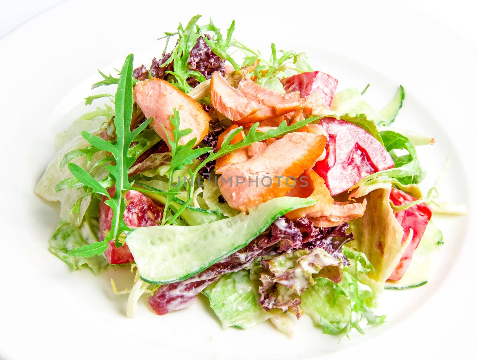 Salad mix with grilled salmon with cucumbers, tomatoes, nuts, cheese sauce on a white plate