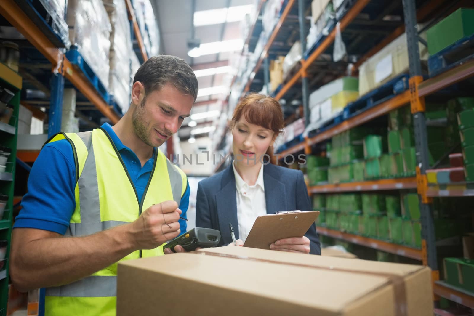 Worker and manager scanning package in warehouse by Wavebreakmedia