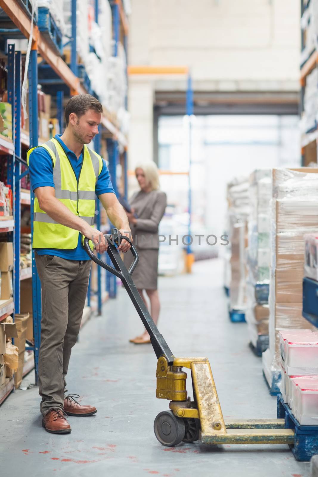 Worker pulling trolley with boxes in warehouse