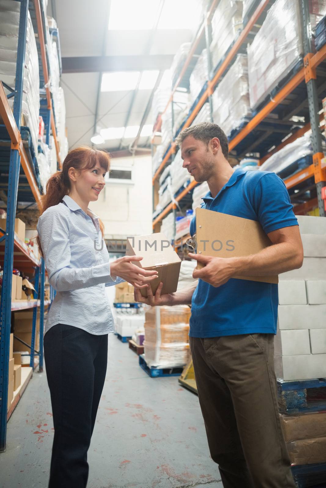 Delivery man passing parcel to warehouse manager by Wavebreakmedia