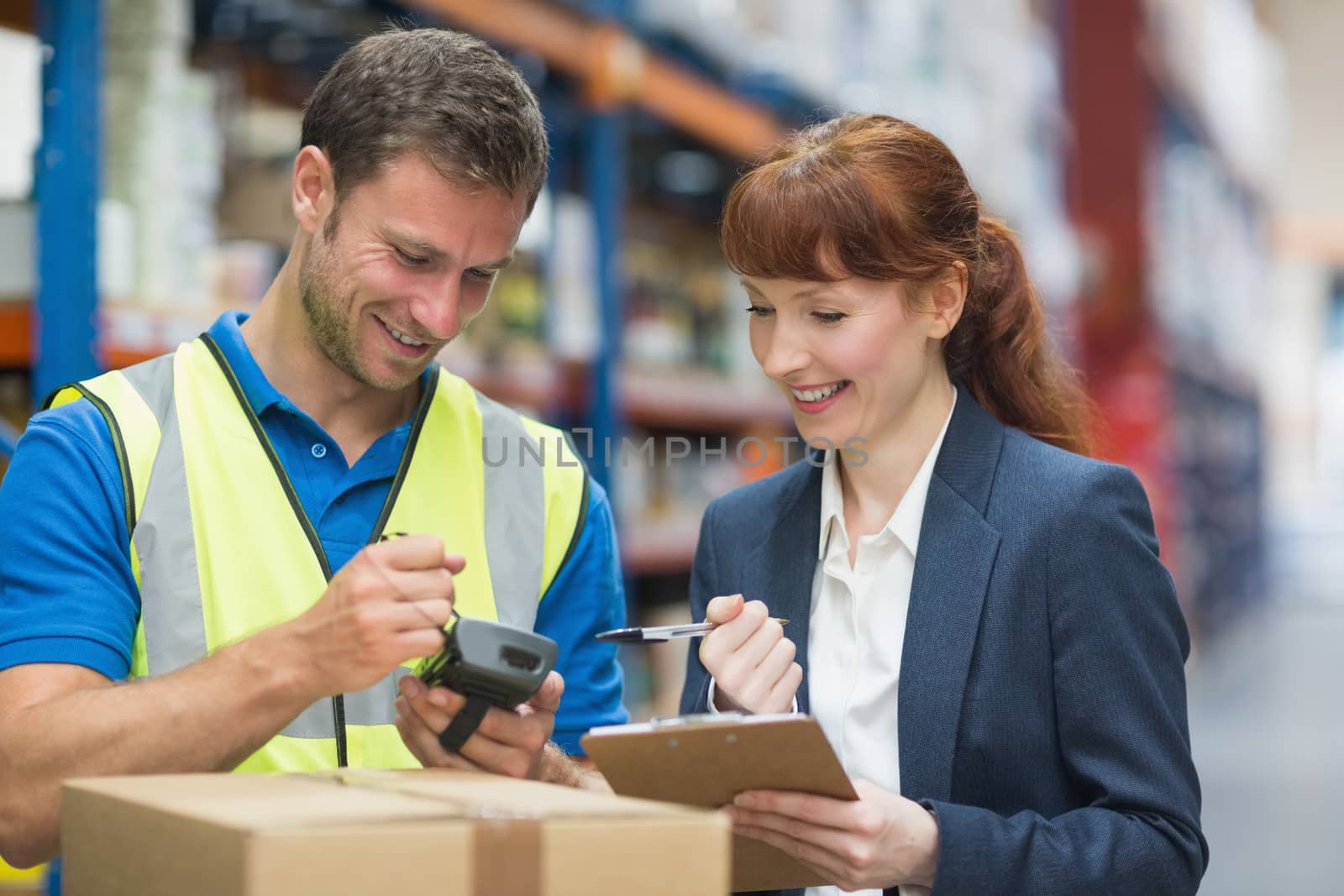 Worker and manager scanning package in warehouse by Wavebreakmedia