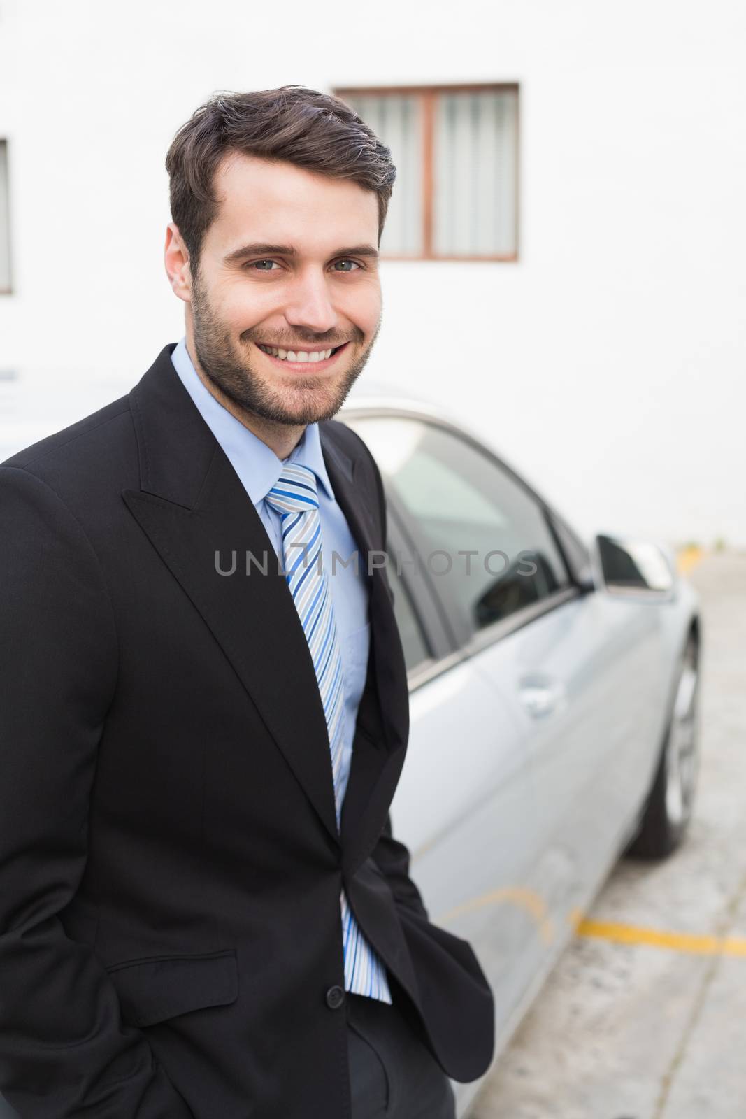 Young businessman smiling at camera outside his car