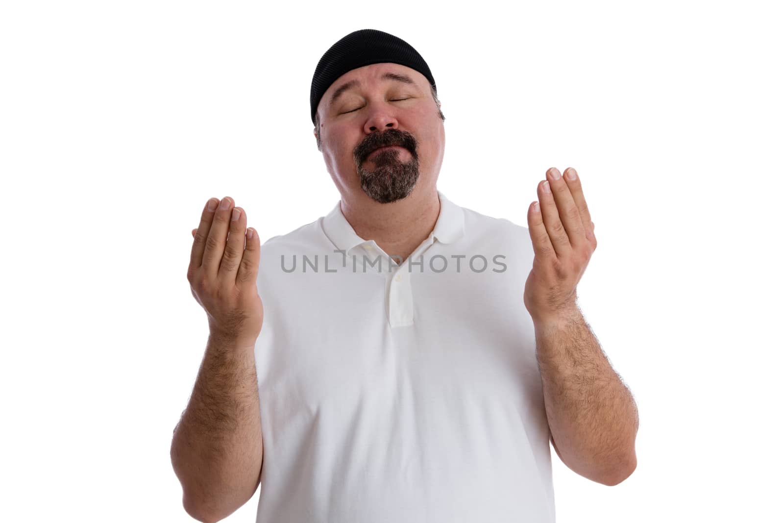 Devout religious middle-aged man deep in prayer standing with is eyes closed and hands raised in supplication, isolated on white