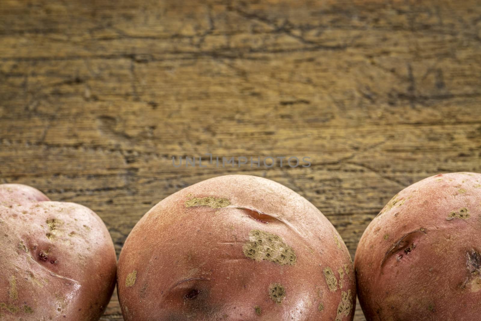 a row of three red potatoes on rustic wood with a copy space