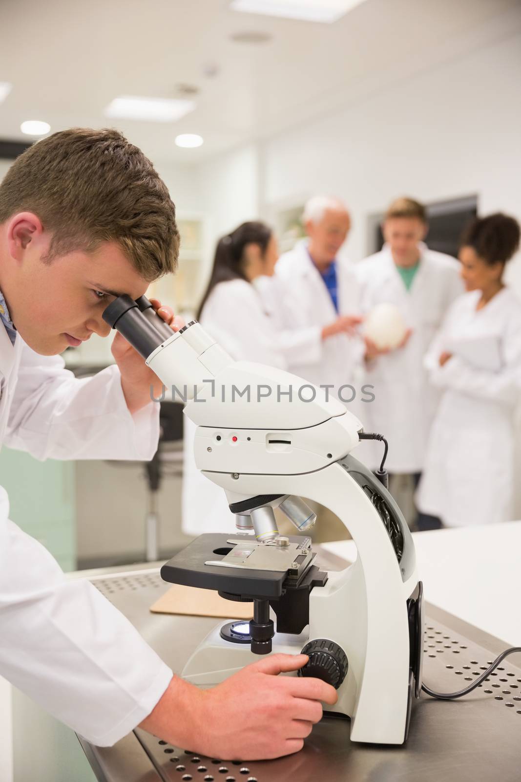 Young medical student working with microscope by Wavebreakmedia