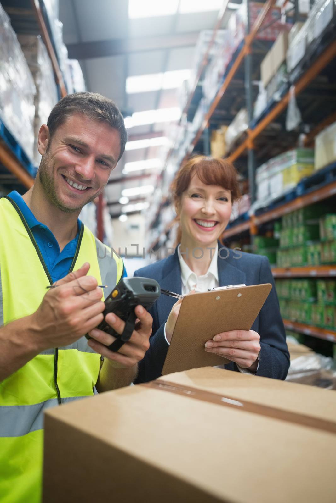 Worker and manager scanning package in warehouse by Wavebreakmedia