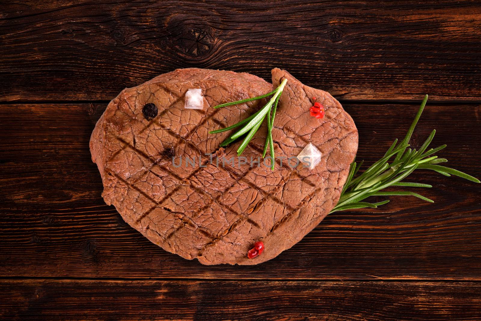 Luxurious tenderloin steak with herbs and peppercorn on vintage wooden background, top view. Steak eating, country style.