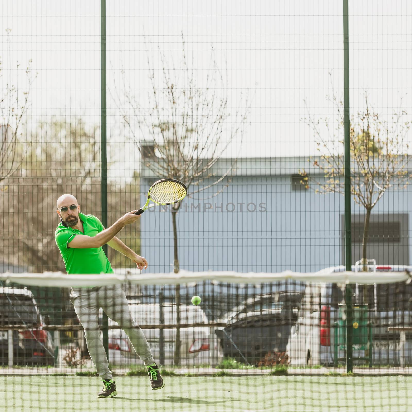 young man play tennis outdoor on tennis field at early morning