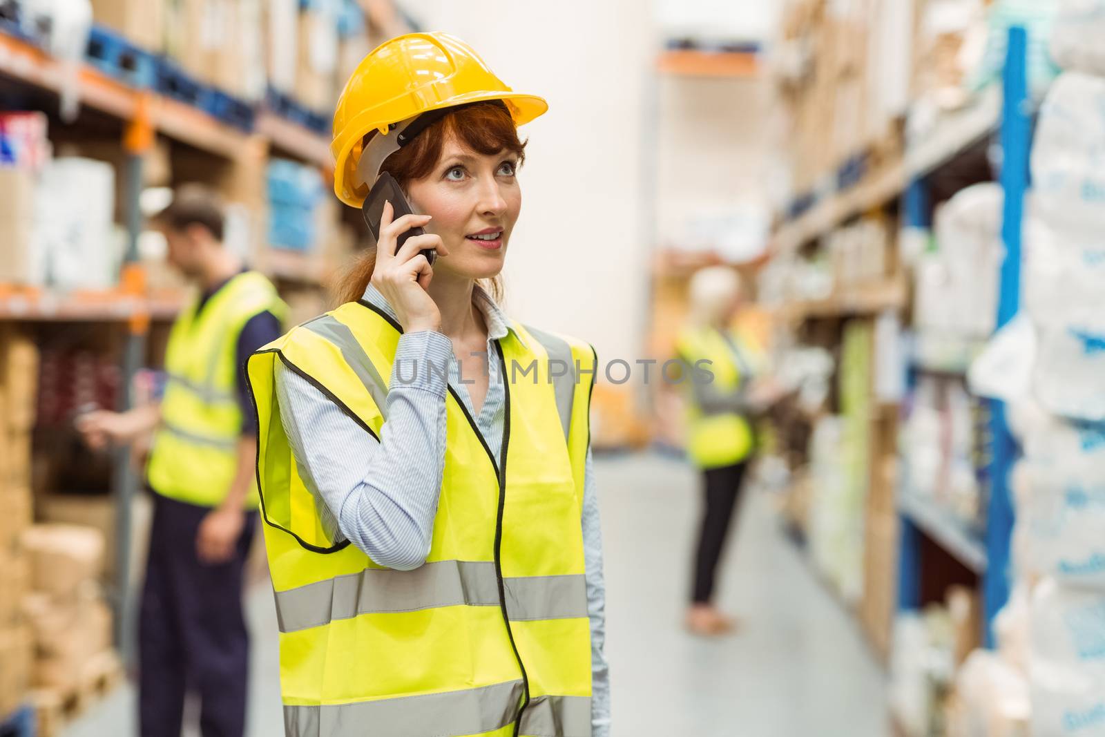Warehouse manager talking on the phone looking around in a large warehouse