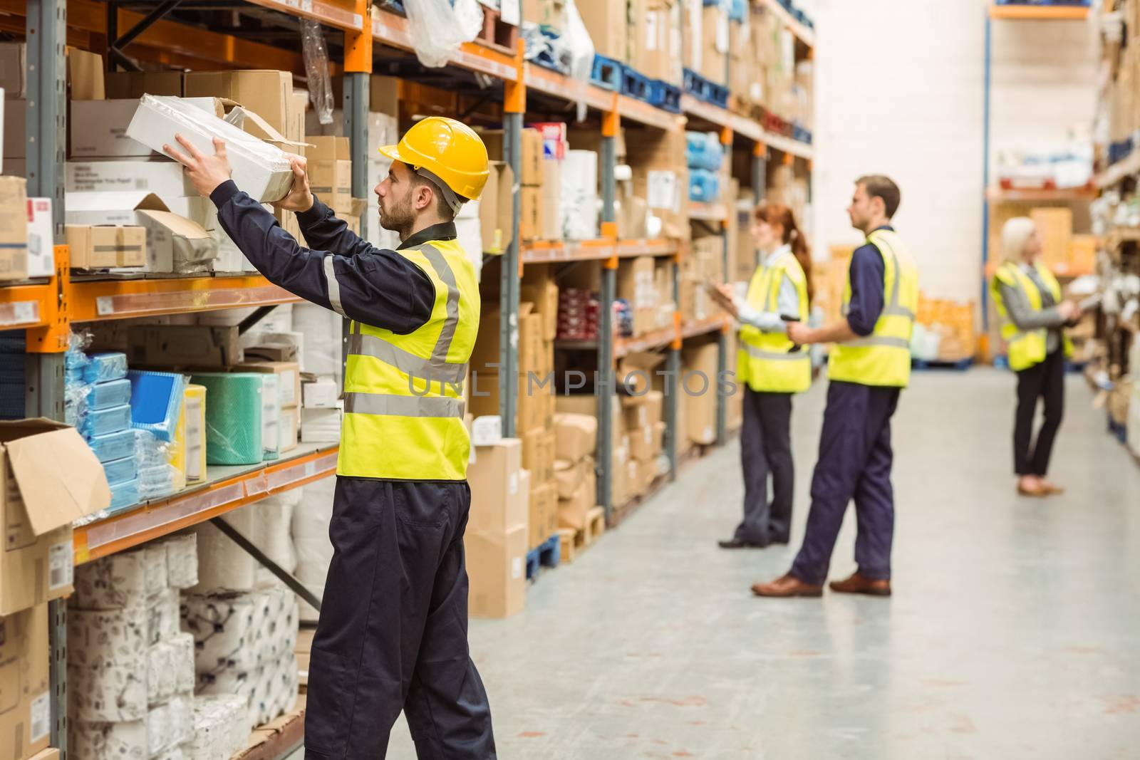 Warehouse worker taking package in the shelf by Wavebreakmedia