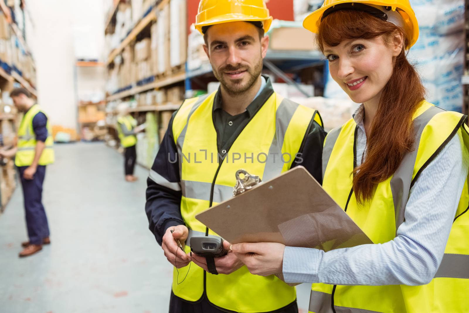 Warehouse team working together with clipboard in a large warehouse