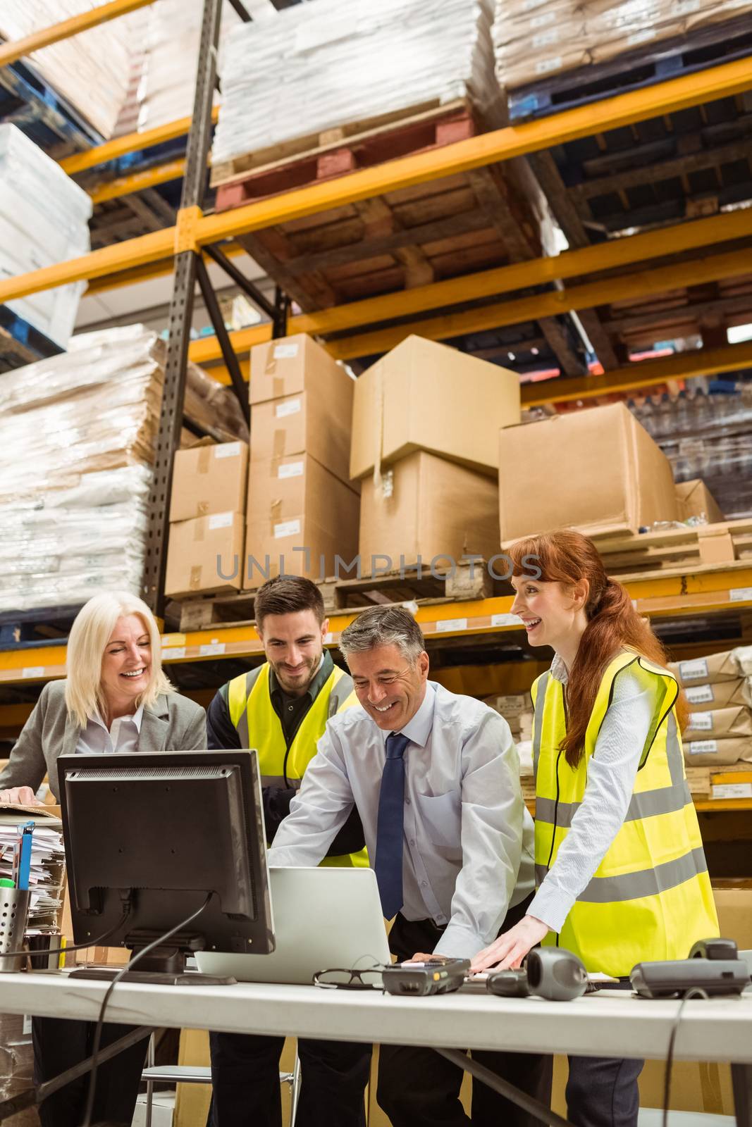 Warehouse team working together on laptop in a large warehouse