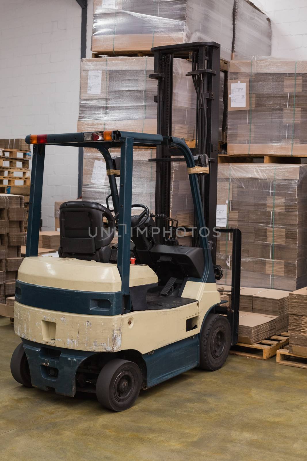 Forklift in a large warehouse by Wavebreakmedia