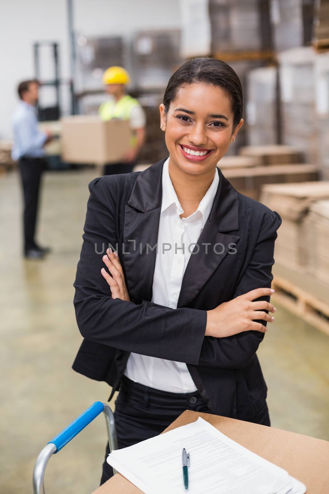 Portrait of smiling female manager with arms crossed in warehouse