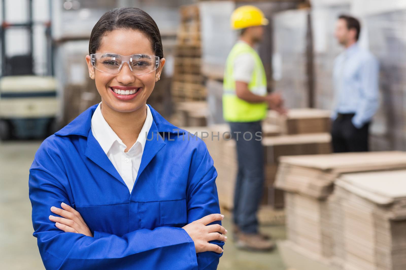 Manager wearing protective mask looking at camera in a large warehouse