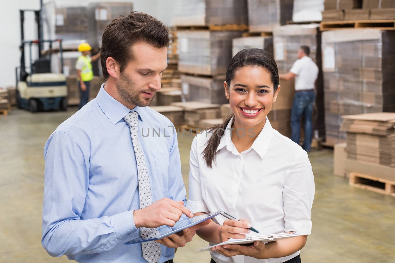 Smiling warehouse managers working together in a large warehouse