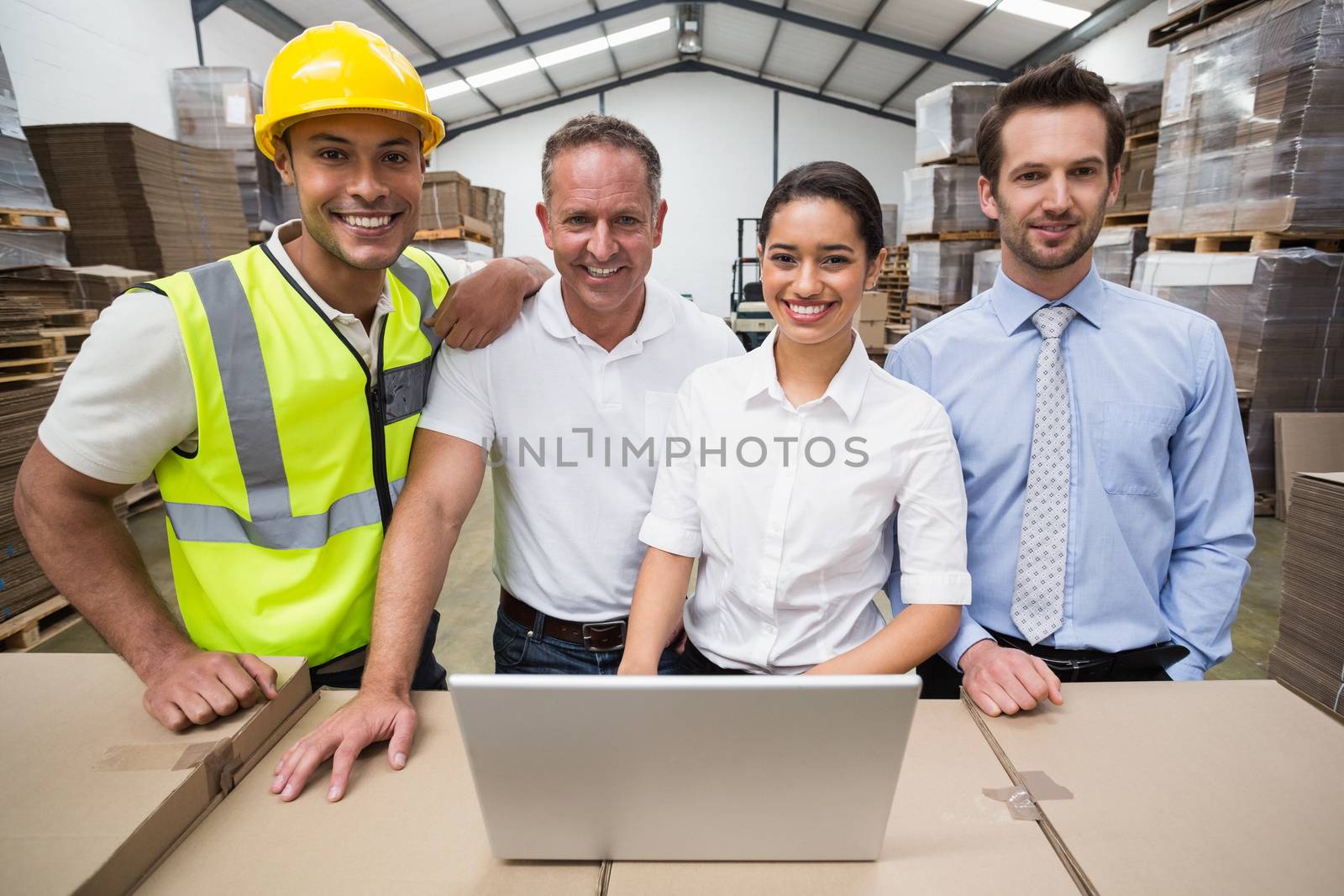 Warehouse managers and worker smiling at camera in a large warehouse