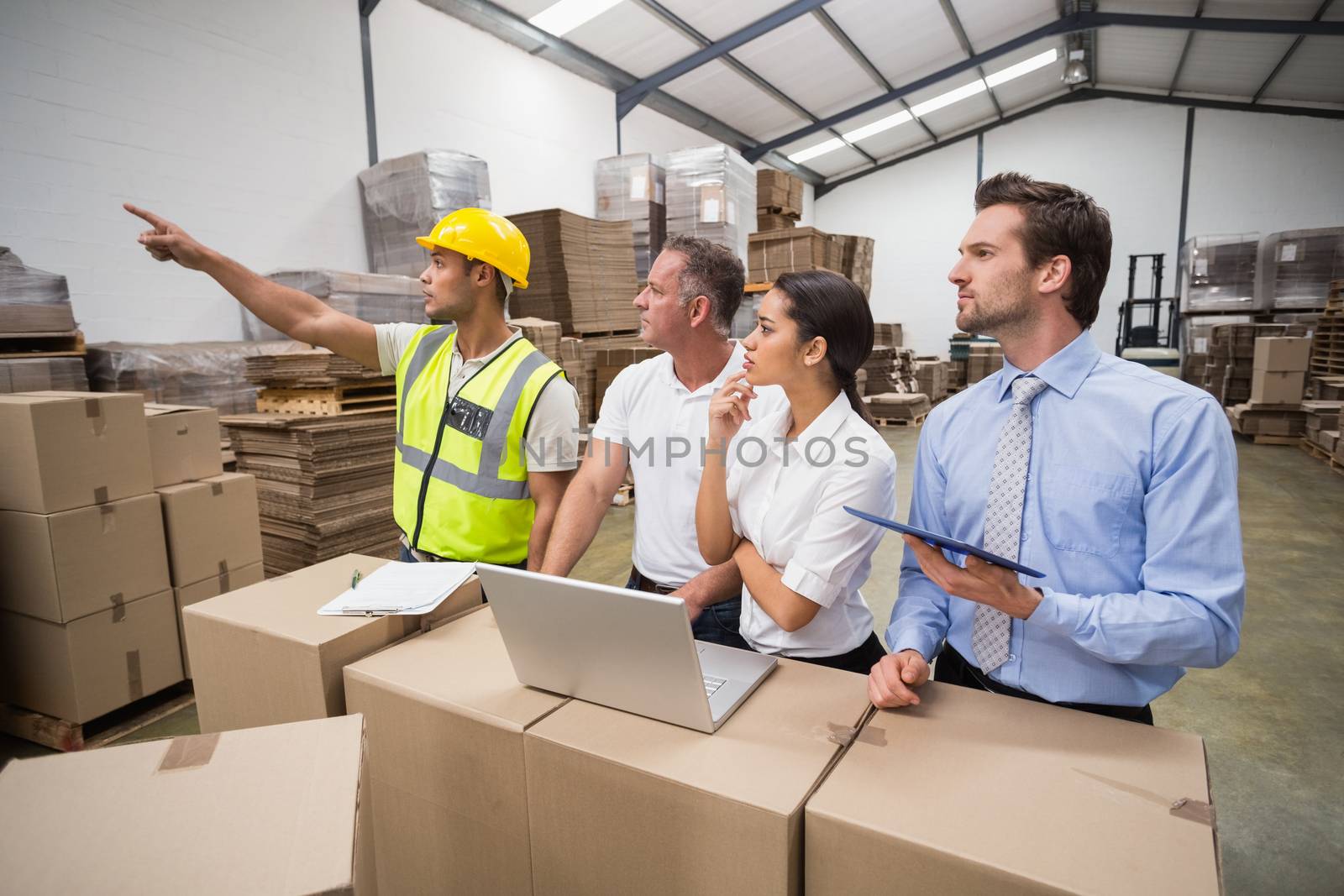 Warehouse worker pointing something to his colleagues in a large warehouse