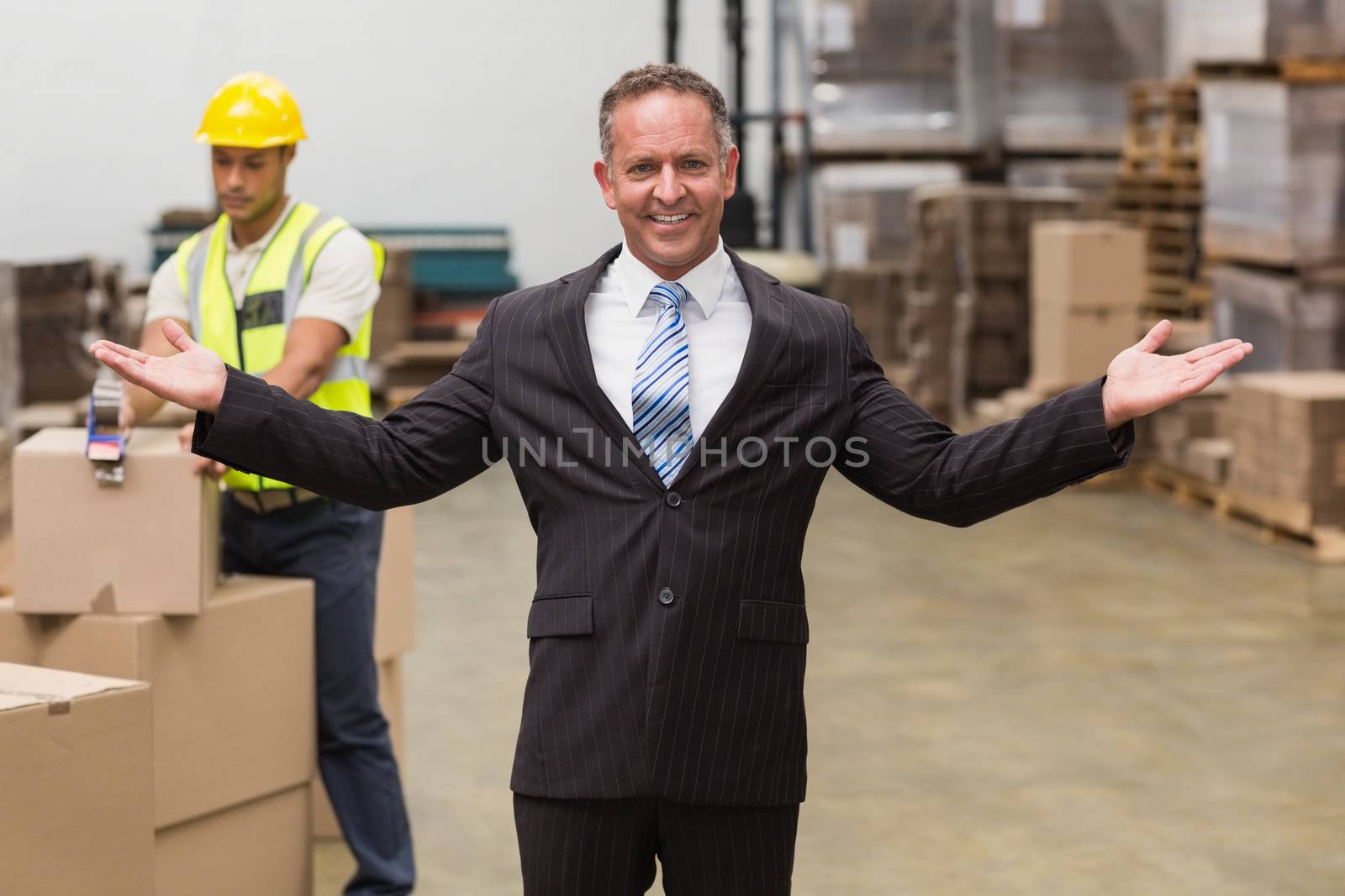 Smiling boss with hands out in a large warehouse