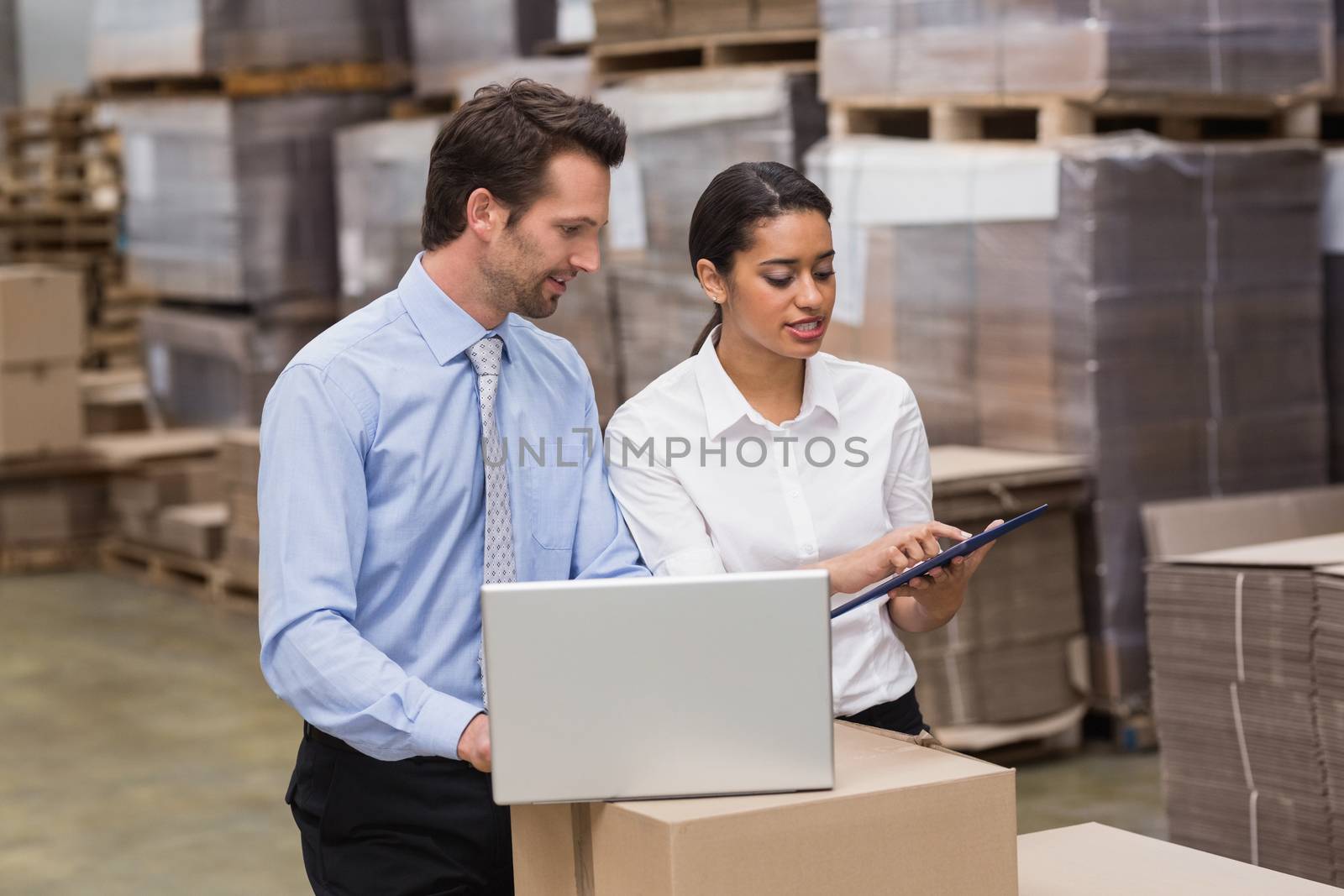 Warehouse managers working on laptop in a large warehouse