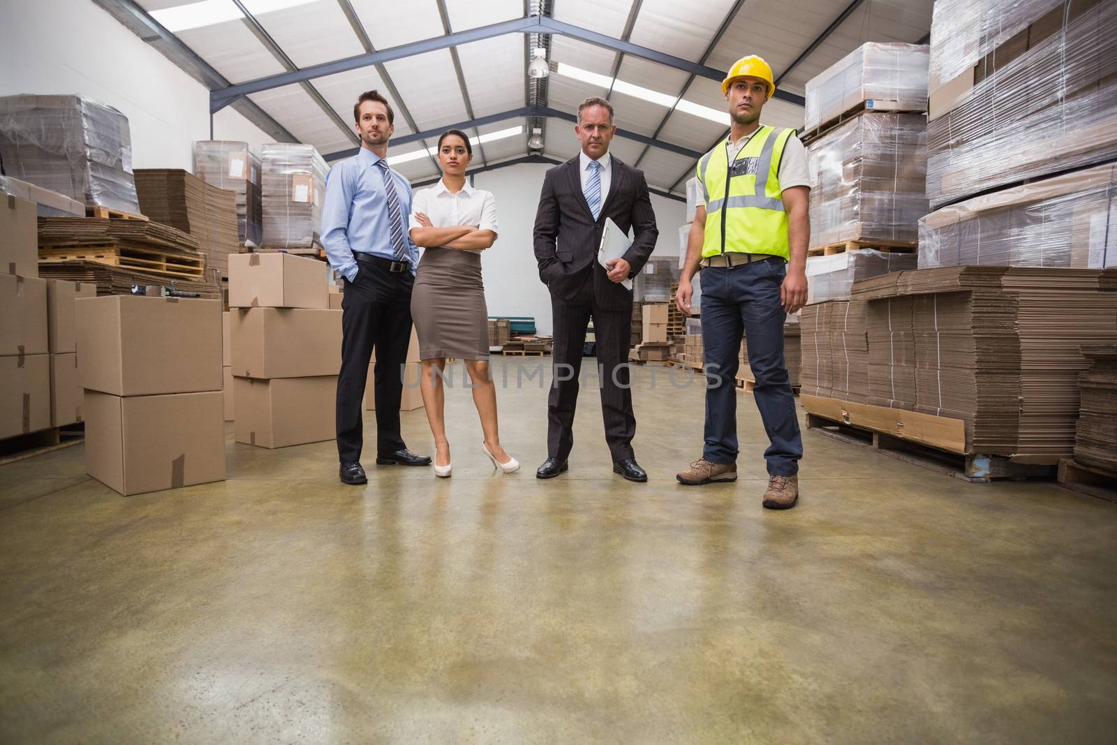 Warehouse team standing looking at camera in a large warehouse