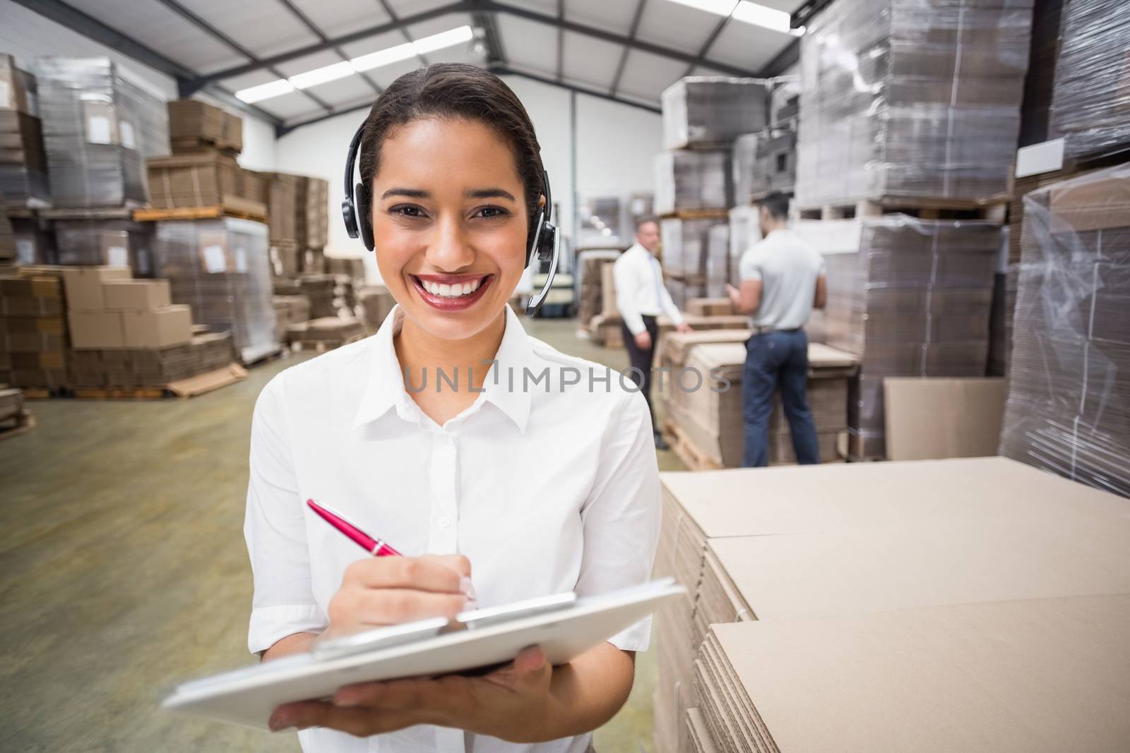 Warehouse manager writing on clipboard in warehouse