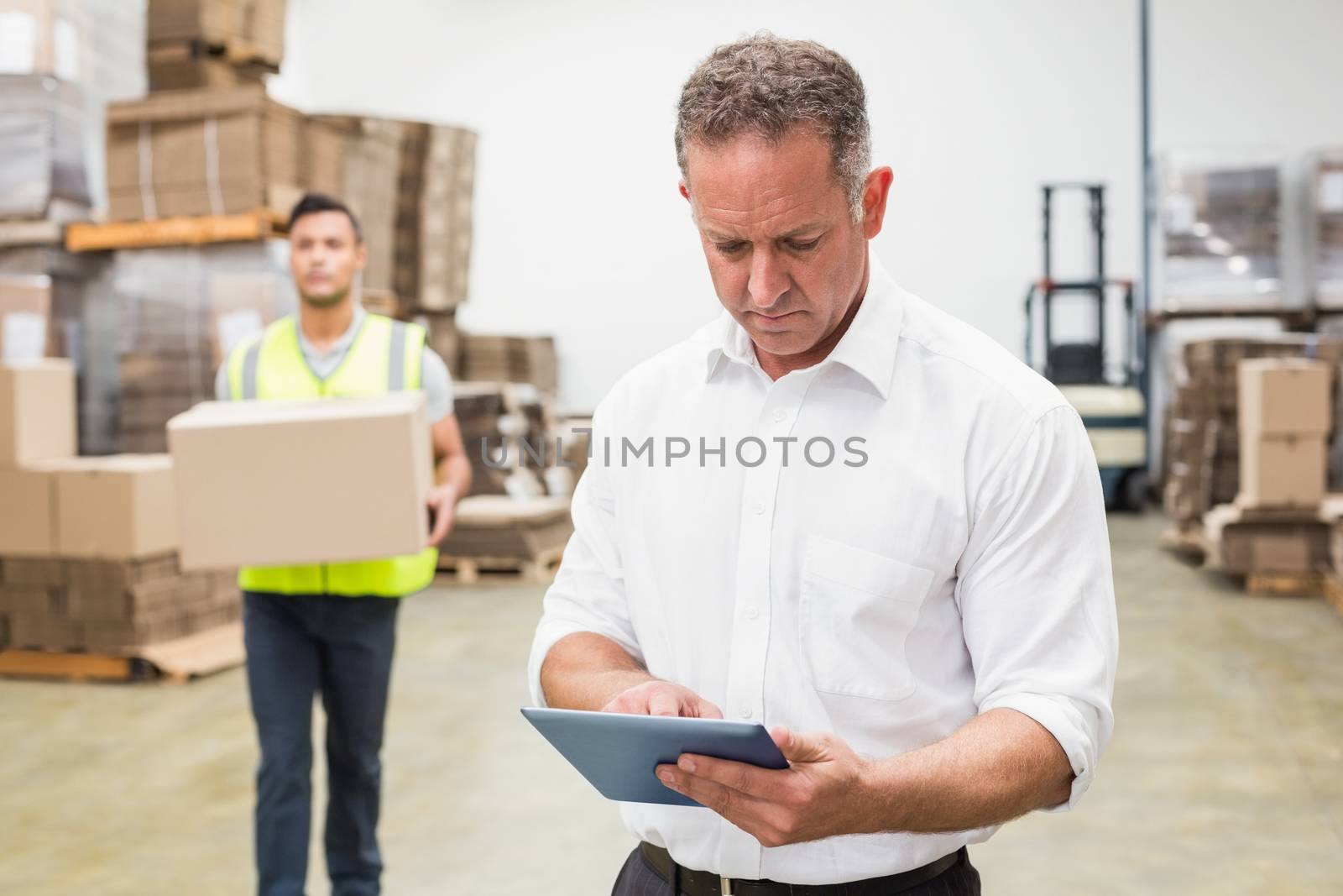 Focused boss using digital tablet in warehouse