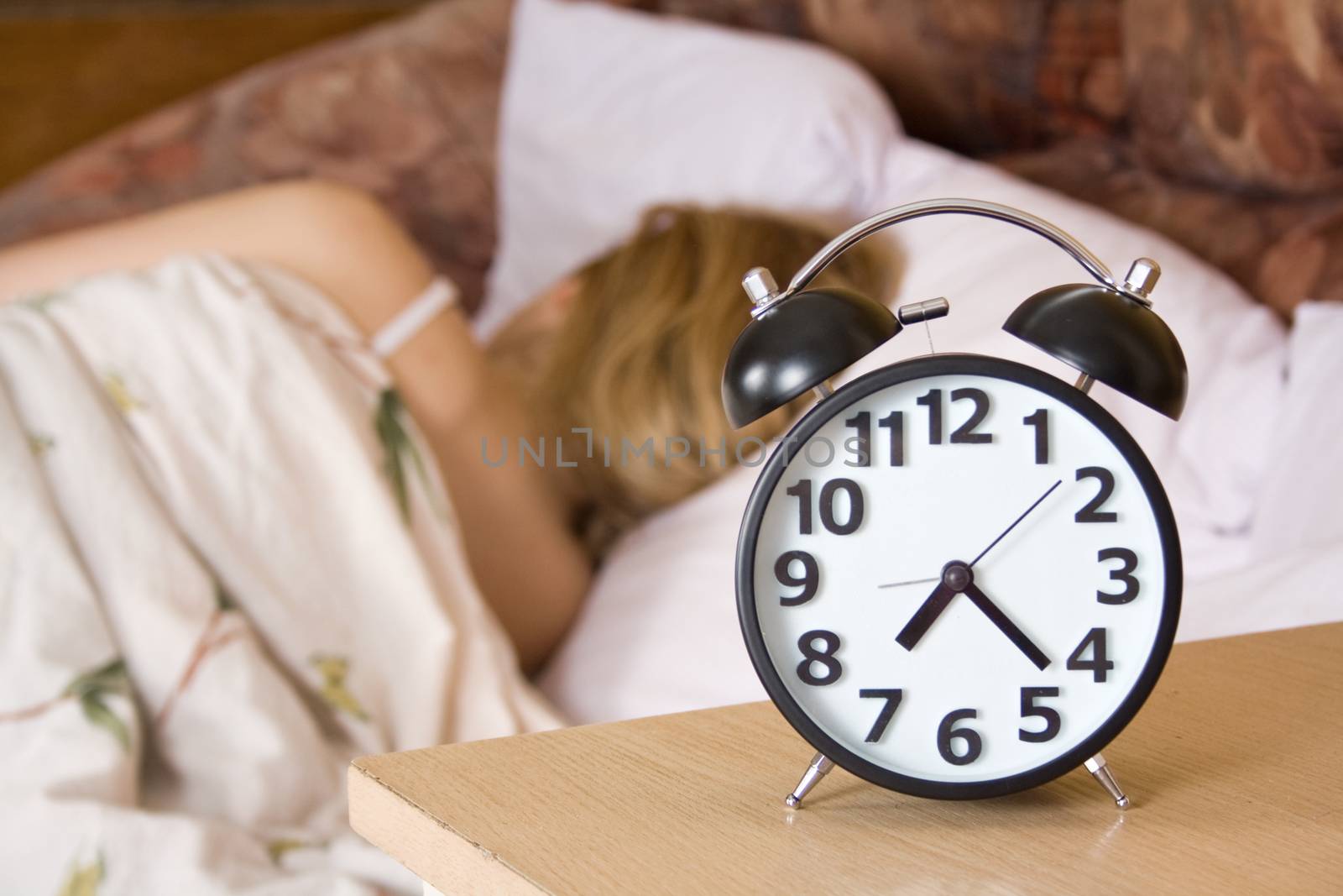 Close up view of table clock and woman sleeping 