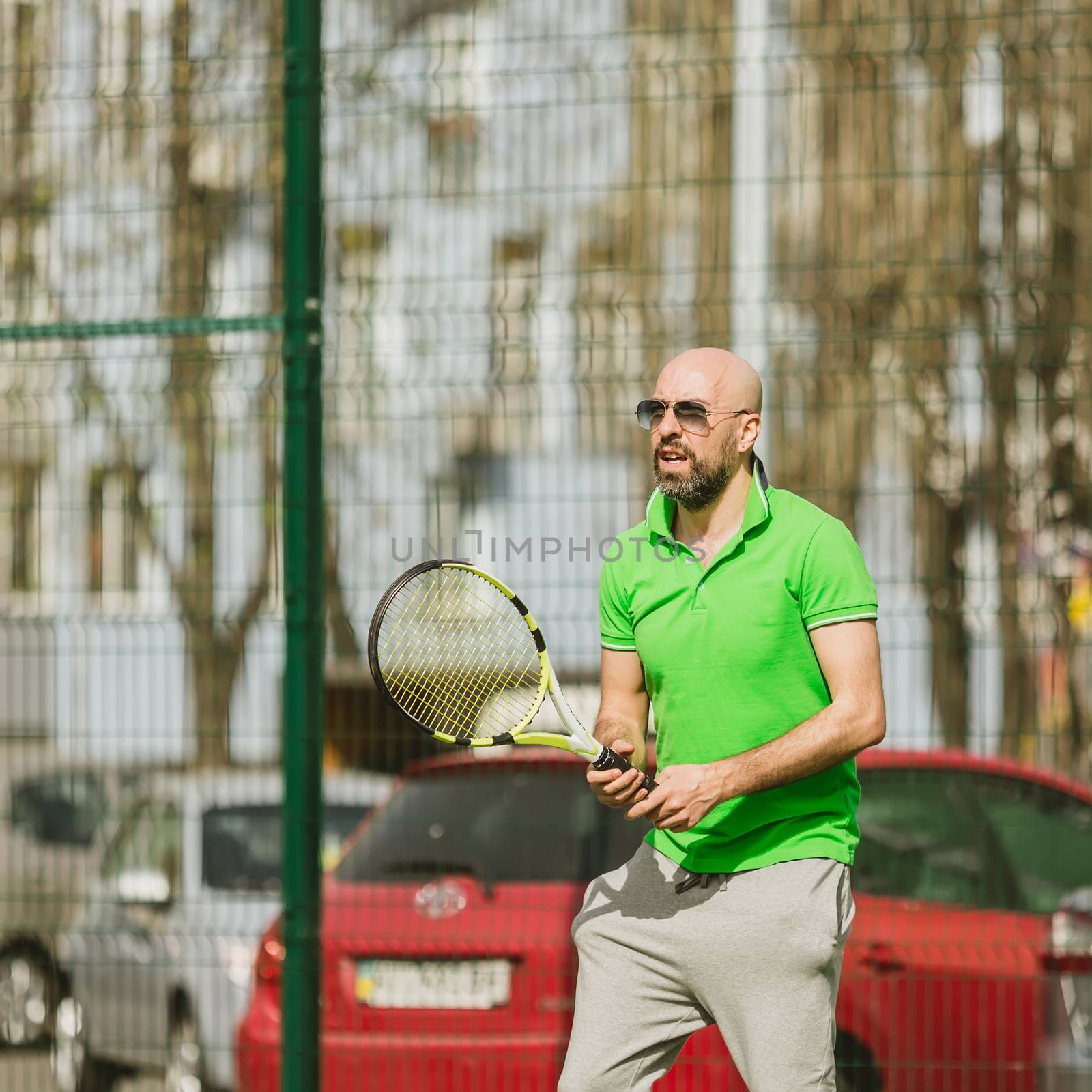 young man play tennis outdoor on tennis field at early morning