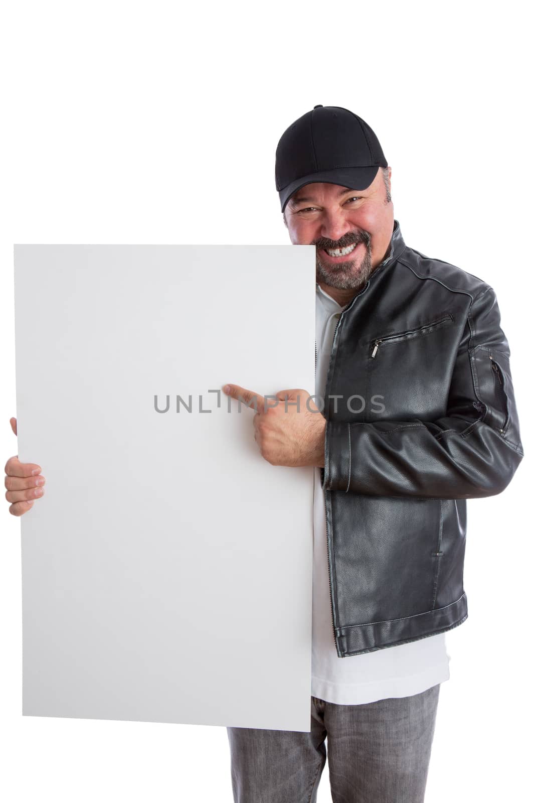 Charismatic trendy middle-aged man in a leather jacket and cap pointing to a blank white sign he is holding with a beaming smile as he promotes your product, isolated on white
