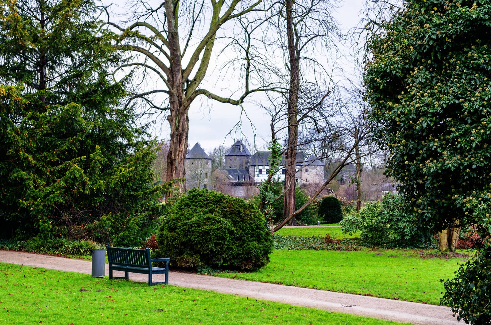 Looking into a park. In the foreground a bench, in the background a castle.