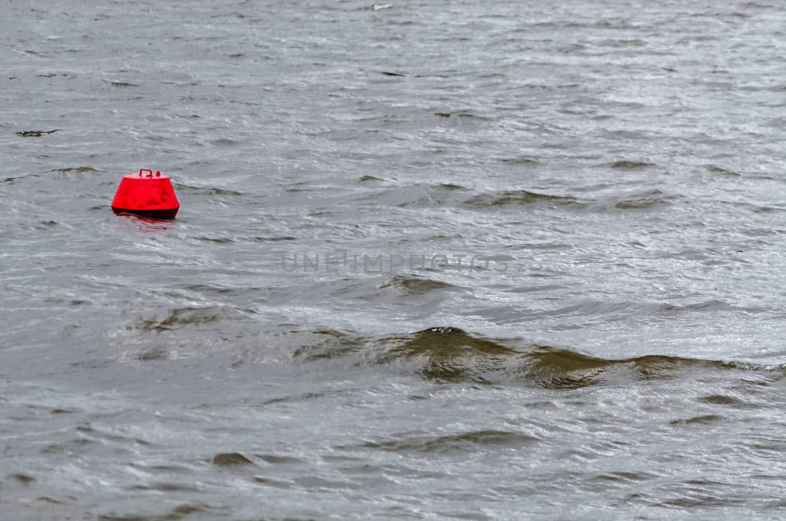 View from a boat on the water in bad weather. In the foreground a red buoy.