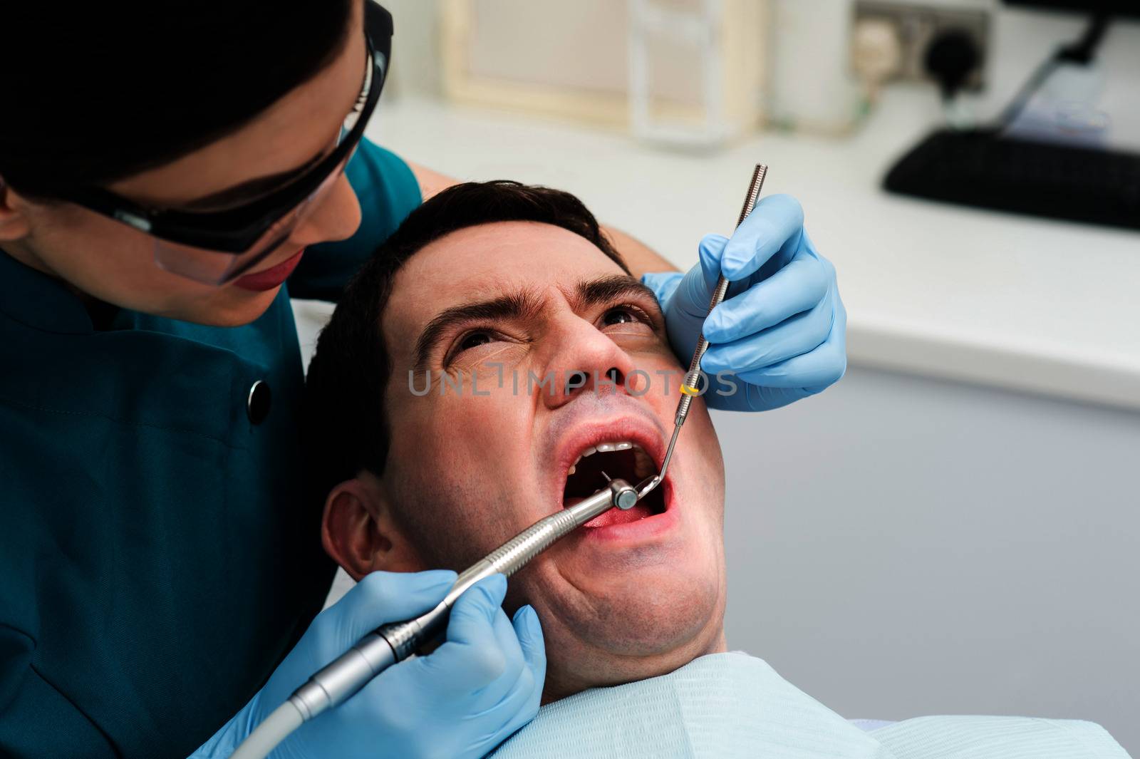 Male with open mouth during oral checkup at dentist