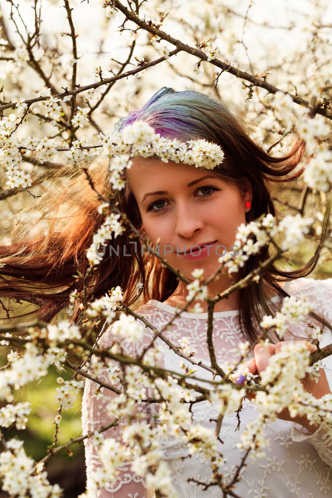 Portrait of cheerful fashionable woman in spring blooming tree, with flowers in hair, retro vintage color