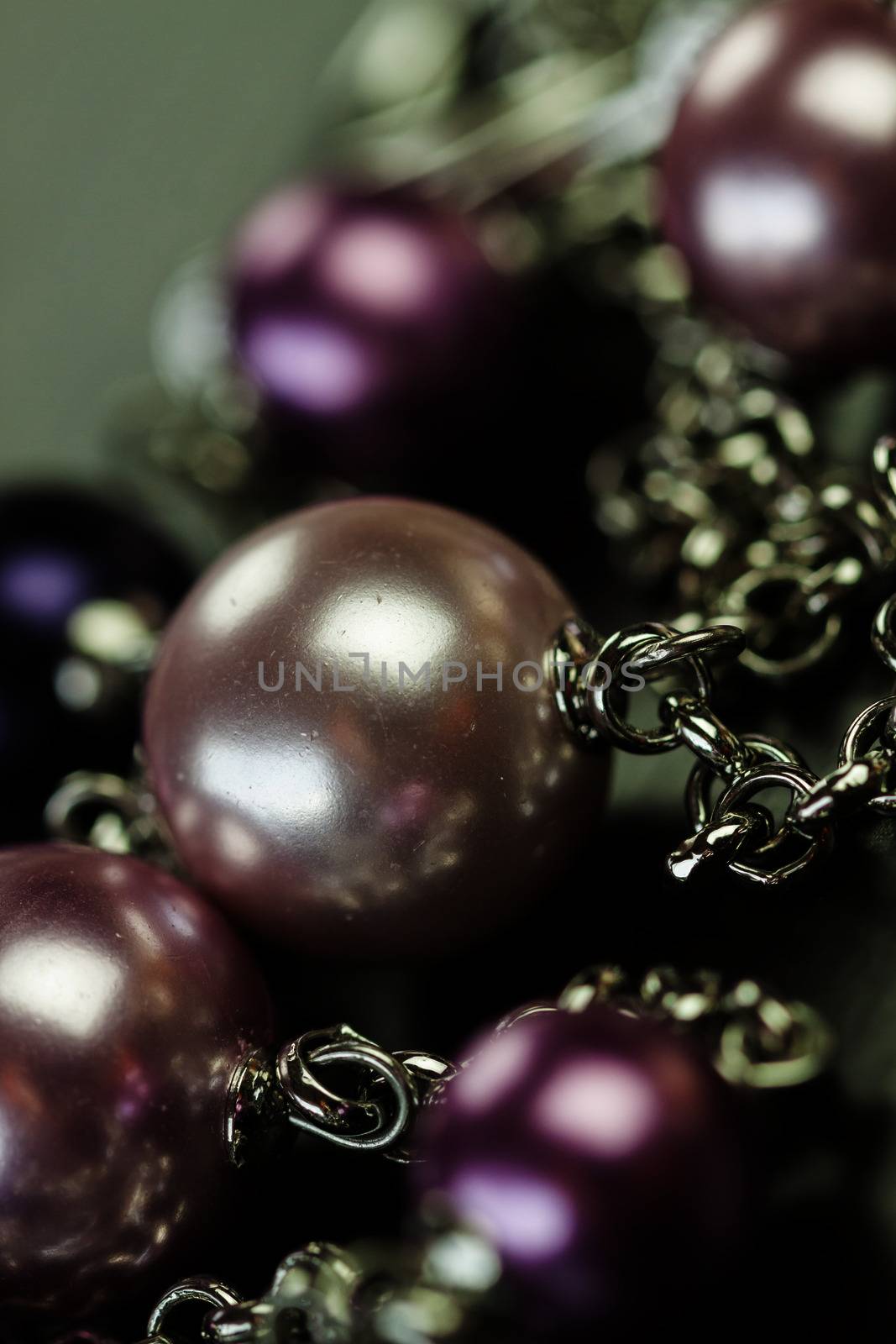 Close up of three attractive shiny purple beads attached by silver chains on an item of jewellery in a fashion and handicraft concept