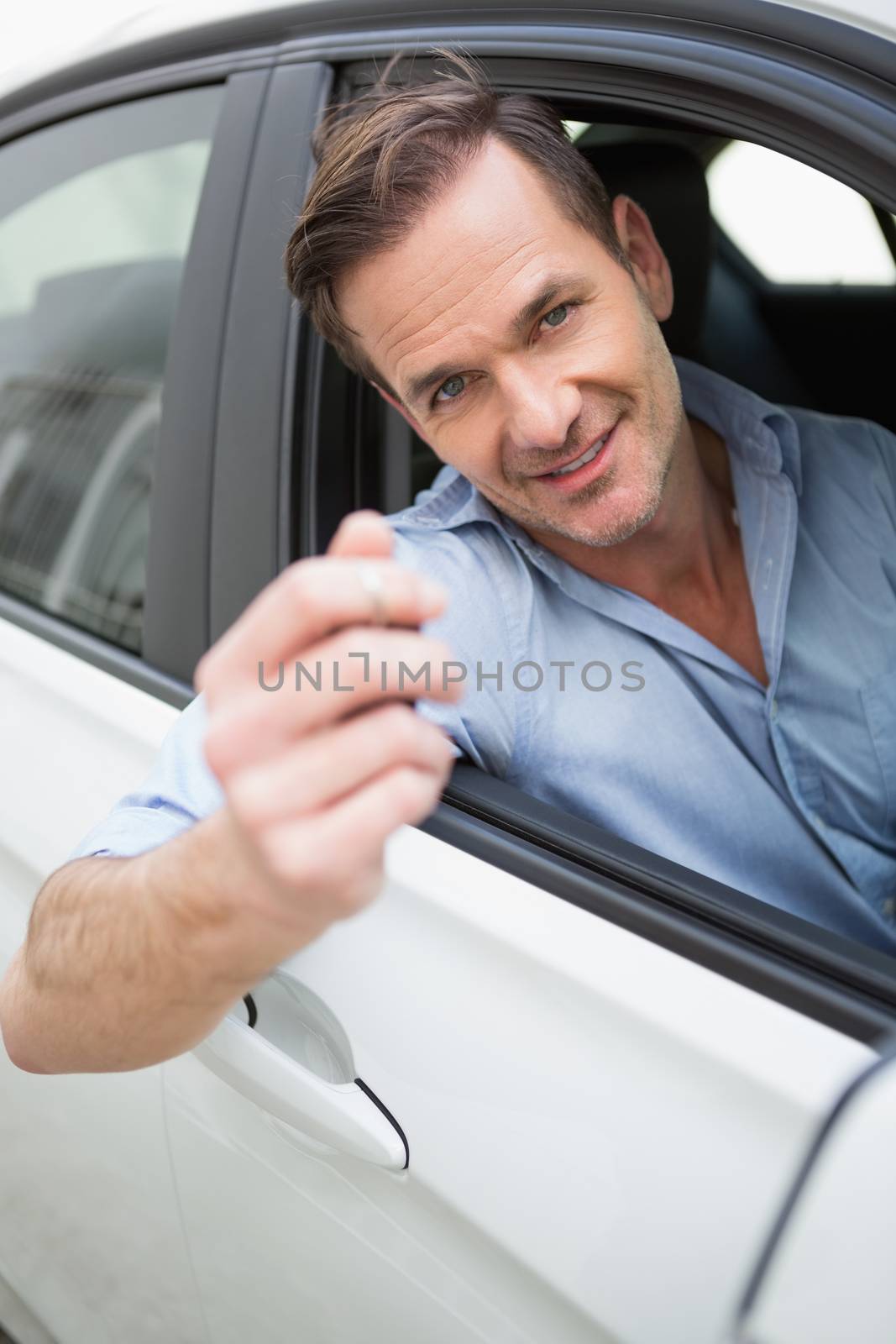 Handsome man smiling and holding key in his car