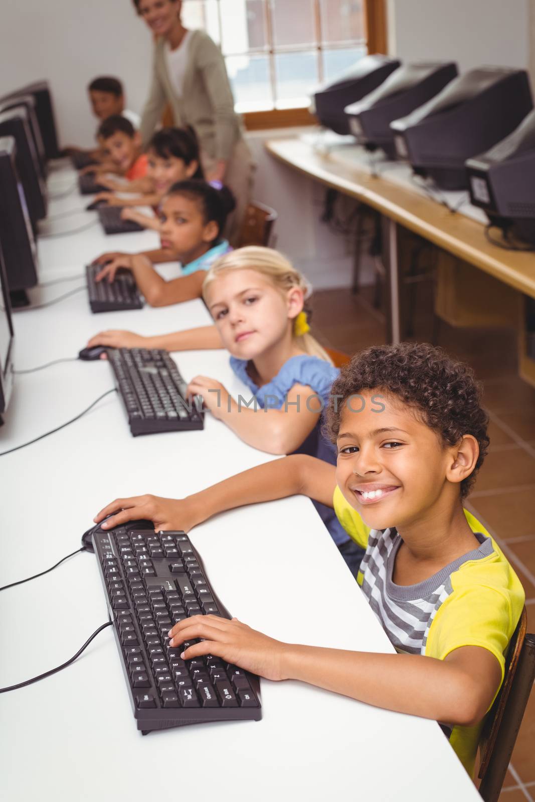 Cute pupils in computer class with teacher at the elementary school