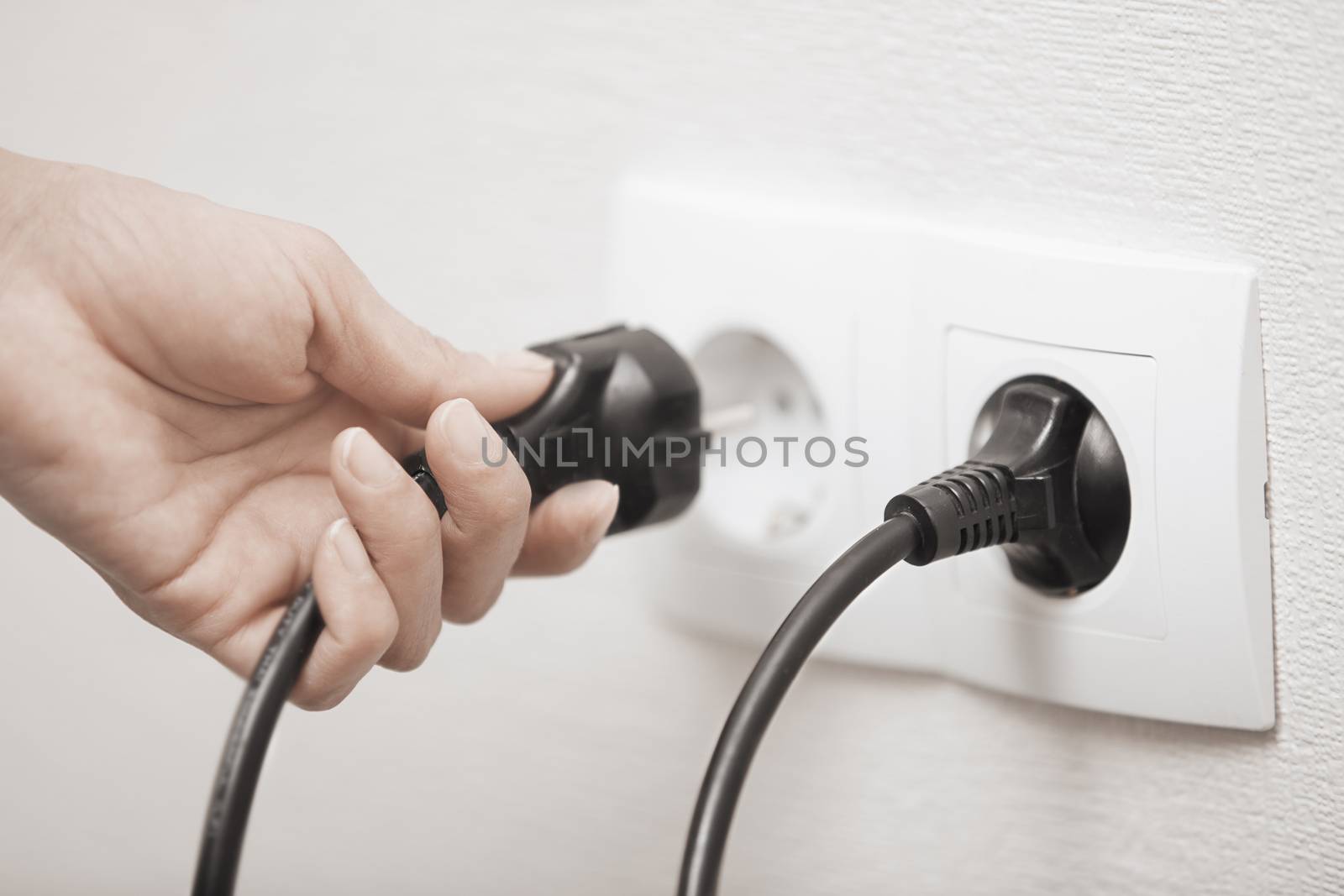 Woman pluging cable to the electric outlet