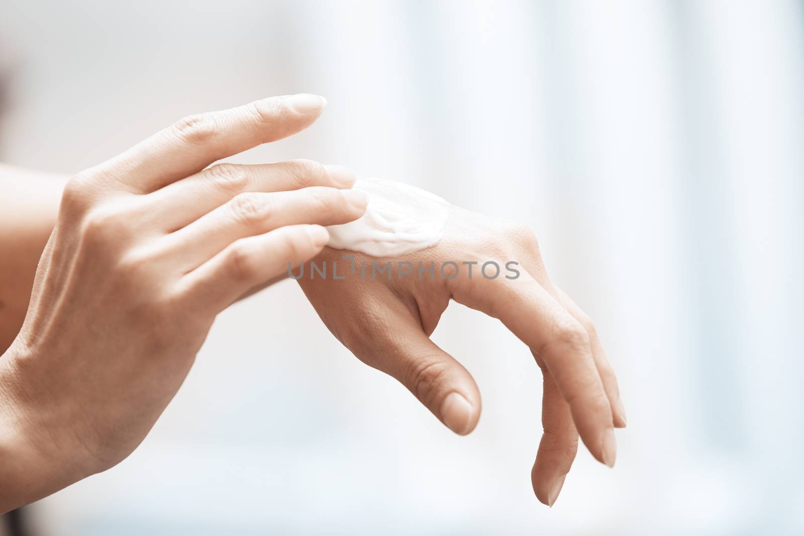 Woman applying moisturizing cream on hands