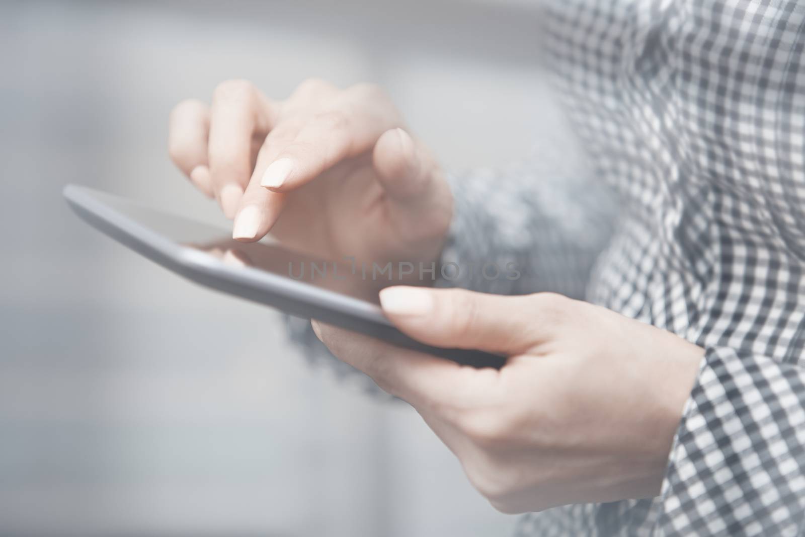 Woman at office behind the glass door working with digital tablet