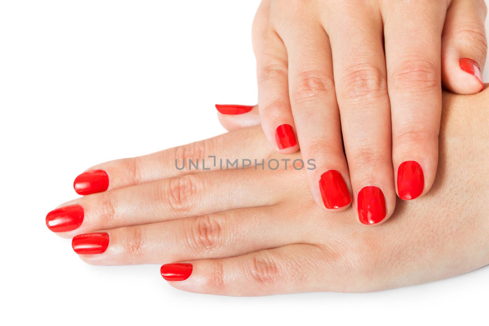 Woman with beautiful manicured red fingernails gracefully crossing her hands to display them to the viewer on a white background in a fashion, glamour and beauty concept